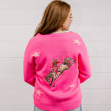 Back view of Woman wearing a bright pink cardigan with star patterns against a white background