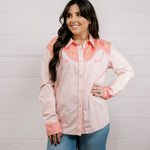 Woman wearing a light pink shirt western shirt with coral & green accents against a white background