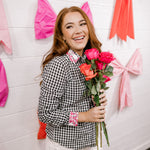 Woman holding flowers in a room with colorful bows on the wall
