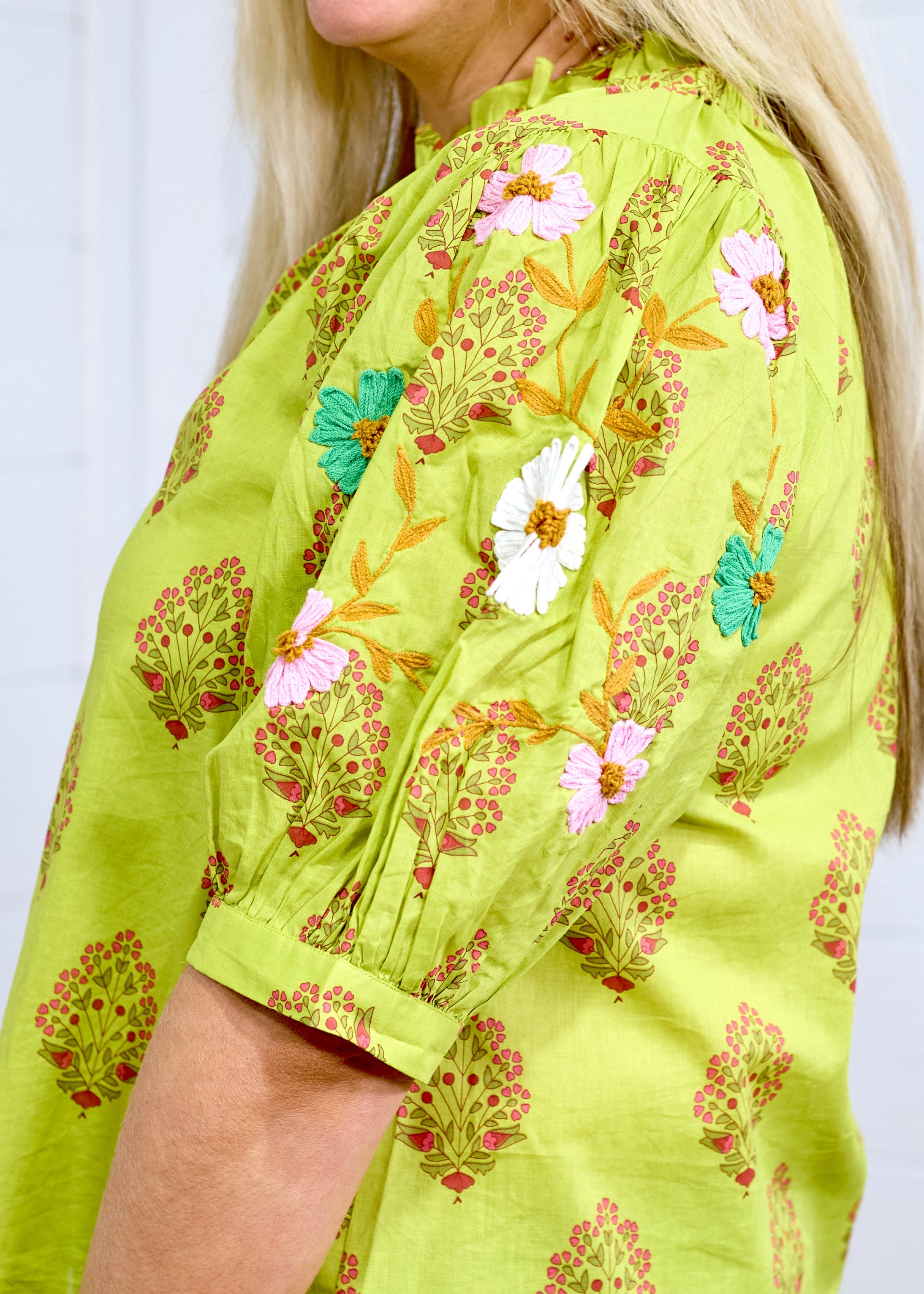 Woman in blonde hair showing in depth perception of sleeve details at a side angle in the Margo Top. The background of picture is white. 