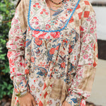 Woman with dark hair standing in a front profile position wearing the Nina Top in a lifestyle scene. The focal point of this image is the blue bordering on chest as well as v-neckline and red/blue patchwork graphics. The model paired this top with light-wash denim jeans. 