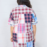 Woman with dark hair standing in a back profile position wearing the Paisley Tunic against a white background. The focal point of this image is to give clear details of the back patches and embroidered on cuffs and collar. 