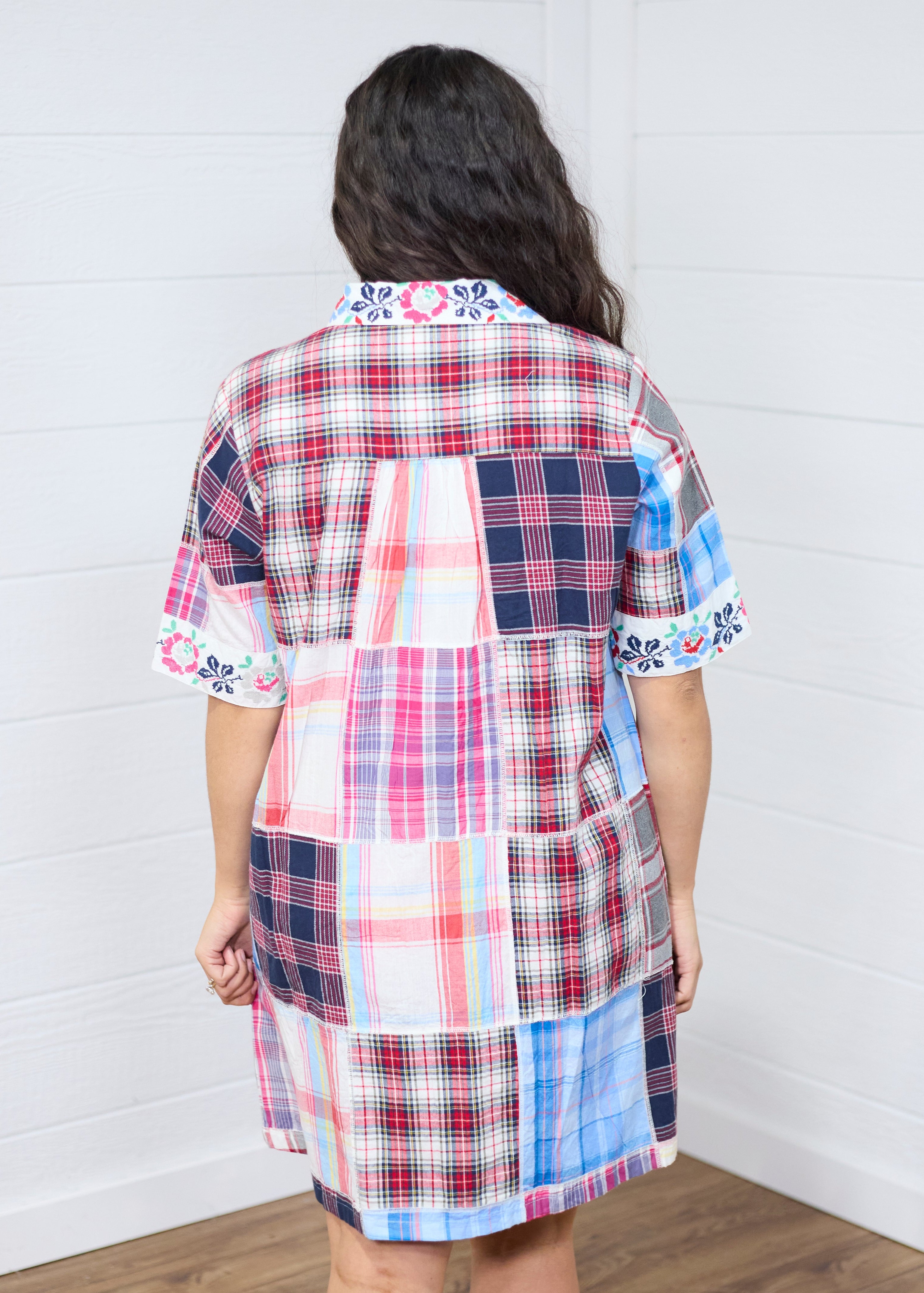 Woman with dark hair standing in a back profile position wearing the Paisley Tunic against a white background. The focal point of this image is to give clear details of the back patches and embroidered on cuffs and collar. 