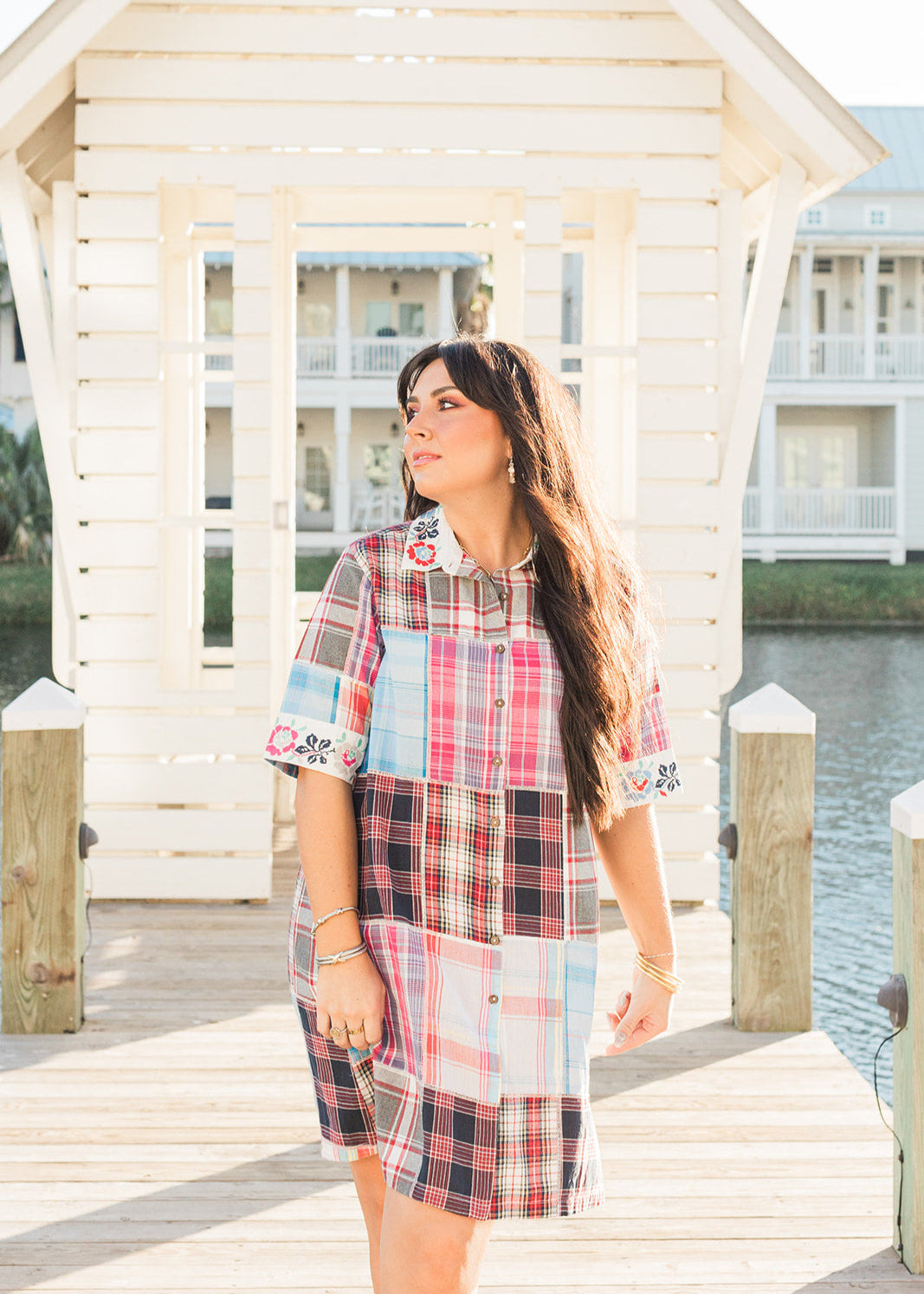 Woman with dark hair standing in a front profile position wearing the Paisley Tunic in a lifestyle scene. The focal point of this image in the entirety of the dress including the patched/favbric, and all embroidery. 