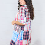 Woman with dark hair standing in a side profile position wearing the Paisley Tunic against a white background. The focal point of this image is the length of dress and embroidery on the sleeves. 