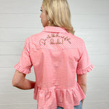Back view women wearing a pink gingham pearl snap top with embroidered on back and ruffles at sleeves and waist. 
