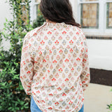 Woman with dark hair wearing a long-sleeve red and blue floral graphic shirt. Model paired this top with dark-wash denim jeans. 