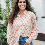 Woman with dark hair wearing a long-sleeve red and blue floral graphic shirt. Model paired this top with dark-wash denim jeans. 