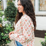 Woman with dark hair wearing a long-sleeve red and blue floral graphic shirt. Model paired this top with dark-wash denim jeans. 