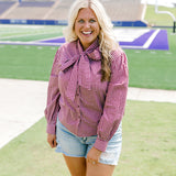 Woman with blonde hair wearing maroon gingham long-sleeve, tied in the front with light-wash denim shorts. 
