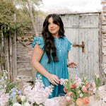 Woman in a blue dress arranging flowers outdoors