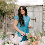Woman in a blue dress arranging flowers outdoors