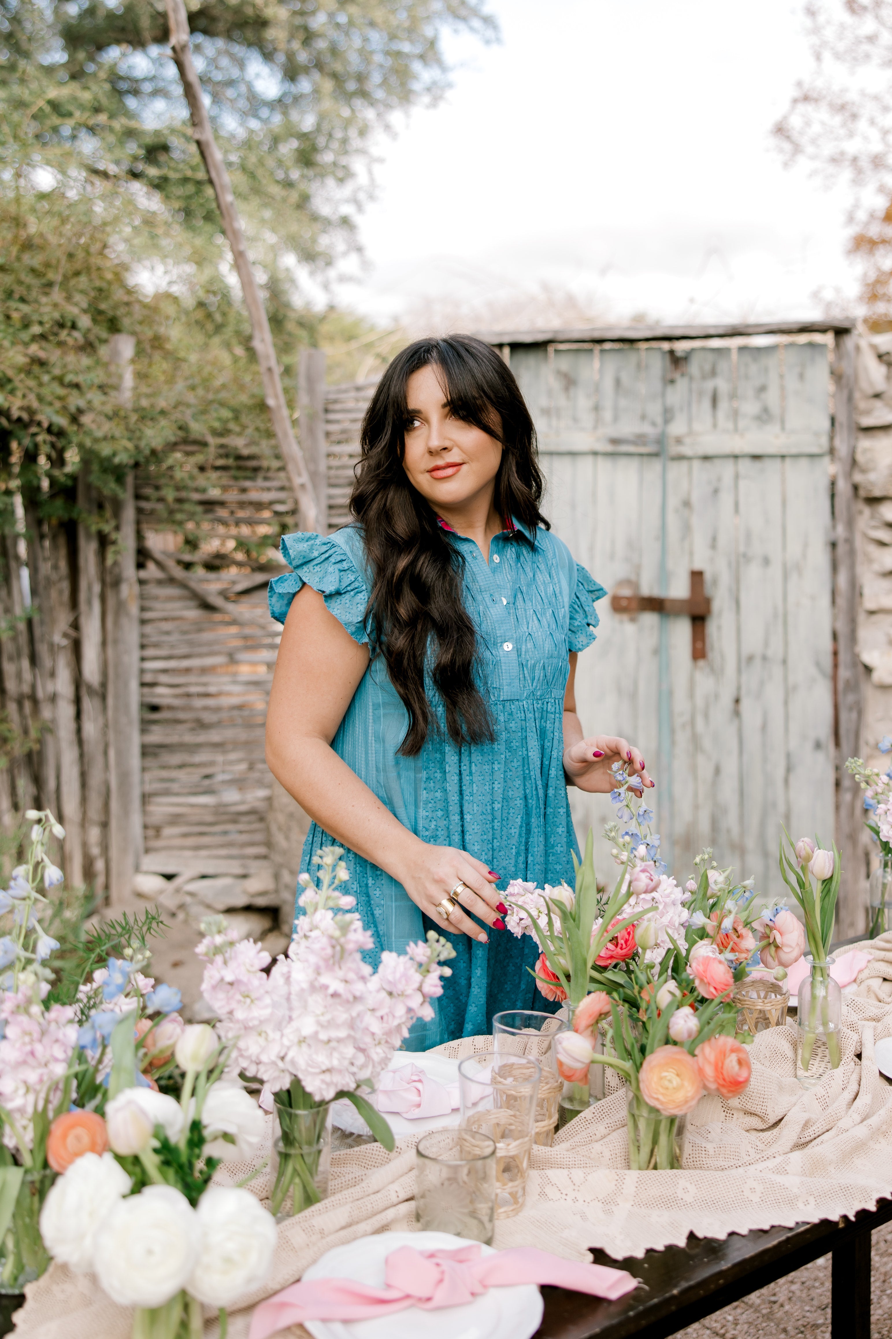 Woman in a blue dress arranging flowers outdoors