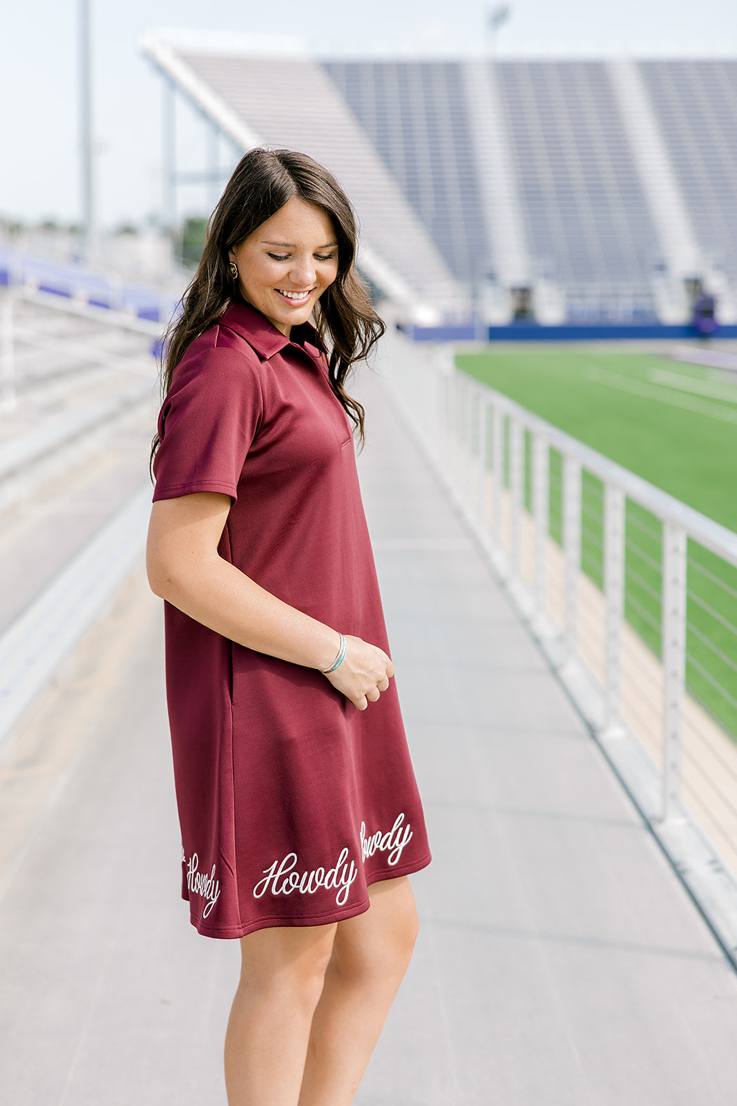 Woman with dark hair wearing a midi maroon dress with howdy embroidery. 