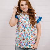 Women wearing a multi colored shirt with a collar and ruffle sleeves showing the front on a white background 