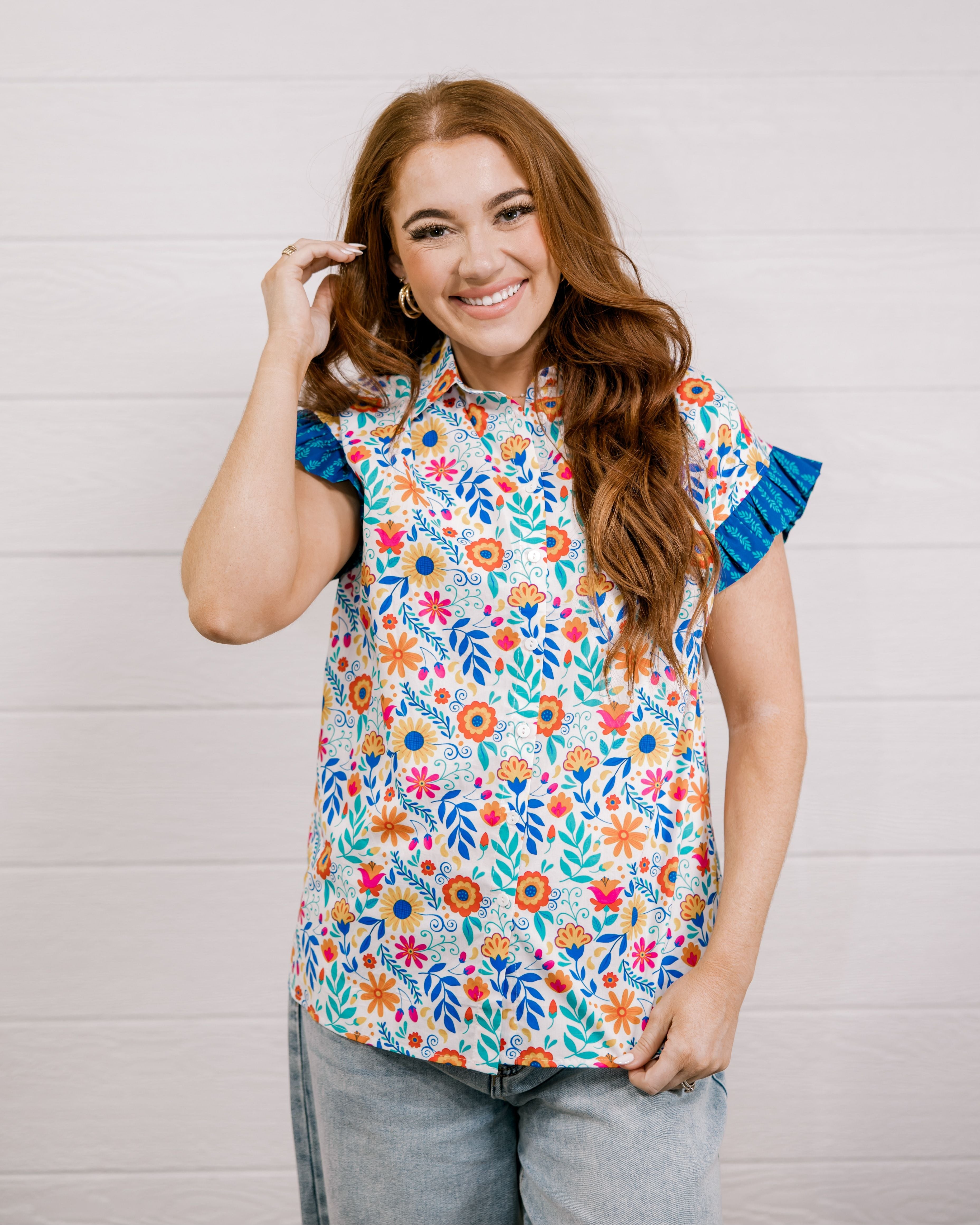 Women wearing a multi colored shirt with a collar and ruffle sleeves showing the front on a white background 