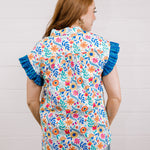 Women wearing a multi colored shirt with a collar and ruffle sleeves showing the back on a white background 