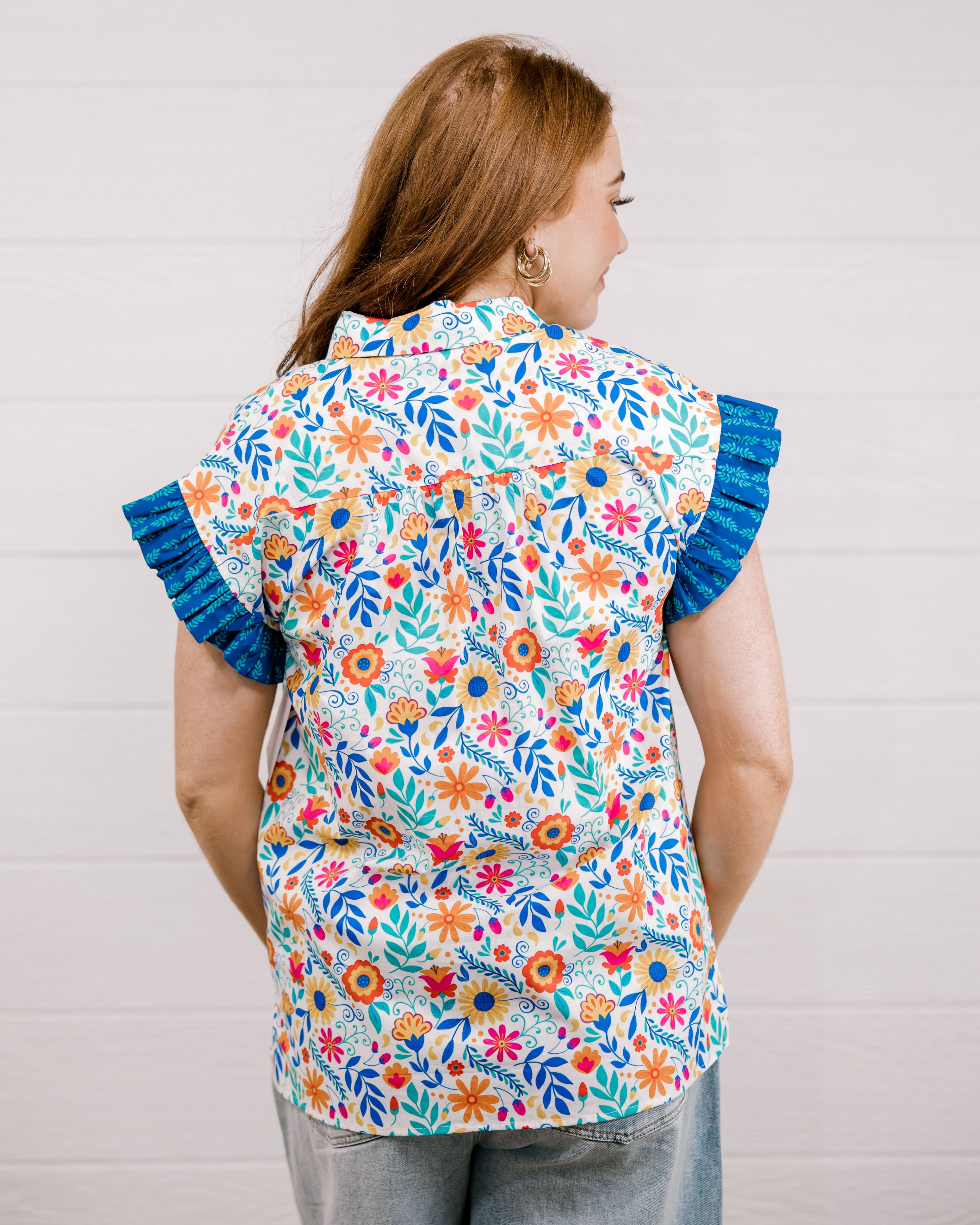 Women wearing a multi colored shirt with a collar and ruffle sleeves showing the back on a white background 