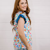 Women wearing a multi colored shirt with a collar and ruffle sleeves showing the side on a white background 