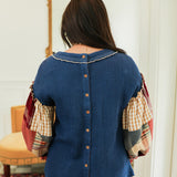 Woman with dark hair standing in a back profile position wearing the Tammy Top in a lifestyle scene. The focal point of this image is the buttons down back of top as well as the patch-work ruffled sleeves. The model paired this top with mid-wash denim jeans.