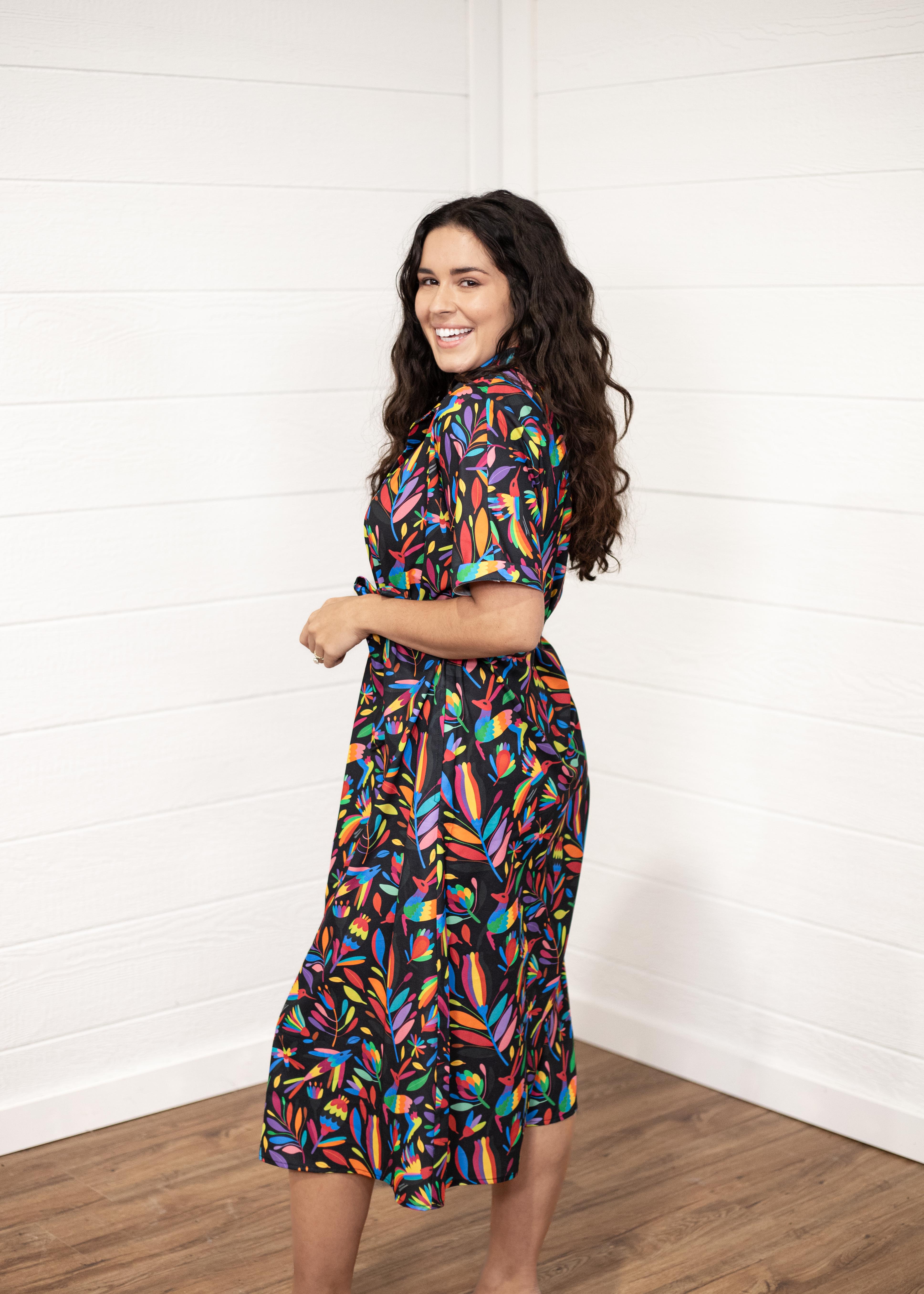 Woman with dark hair in a side profile position wearing the Vanessa Dress against a white background. The focal point of this image is the graphics on side of dress with emphasis on the sleeve area. 
