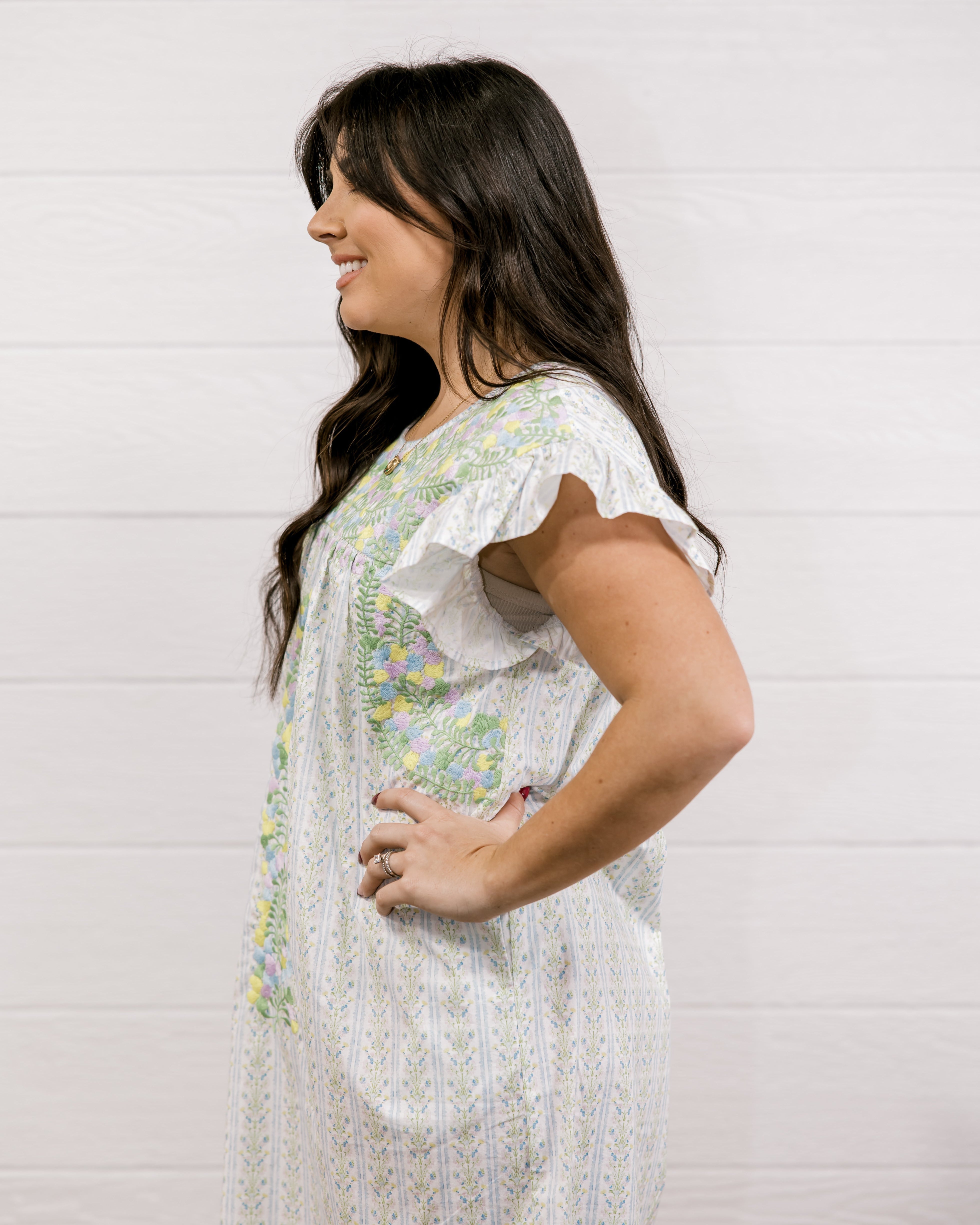 Woman wearing a white floral dress against a light background