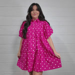 Women wearing pink polk a dot dress on white white twirling. 