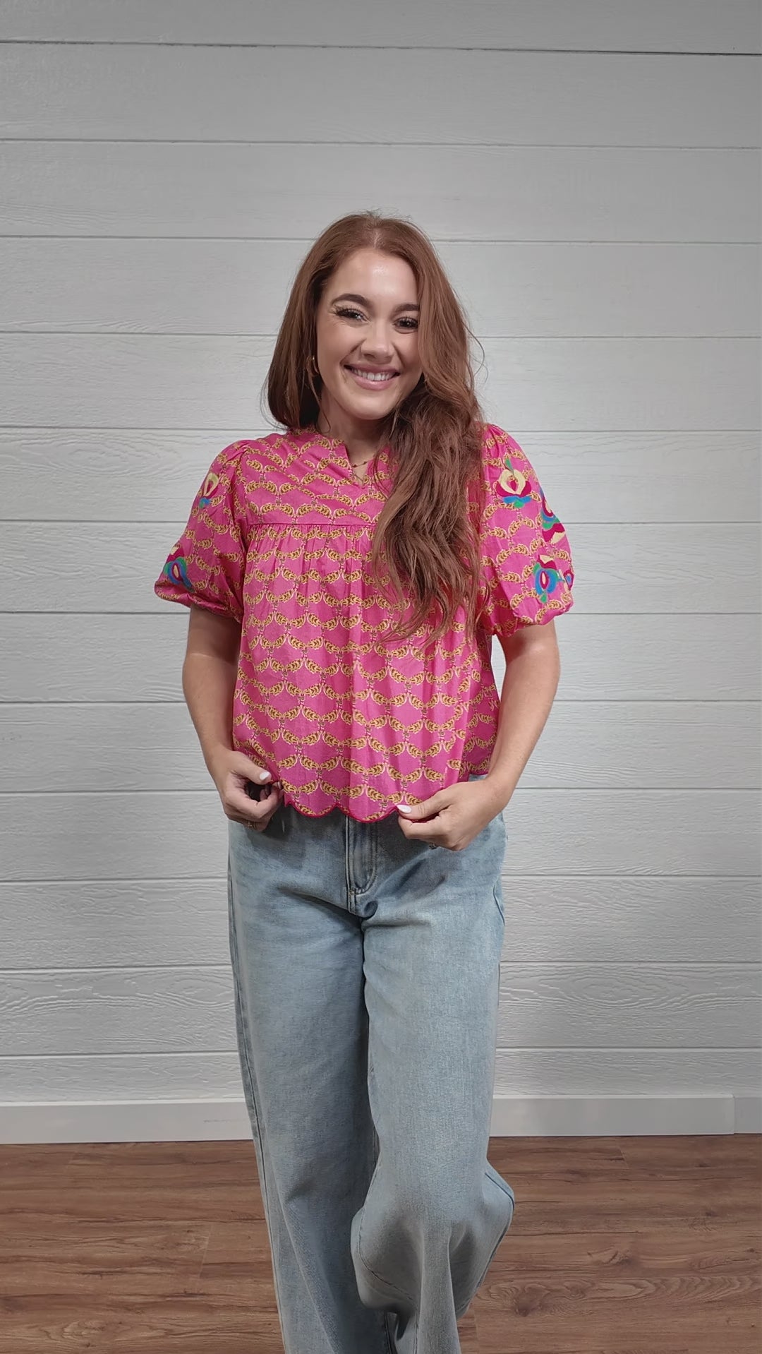 Video of woman wearing colorful pink top in front of white wall. front facing, side facing, and back facing